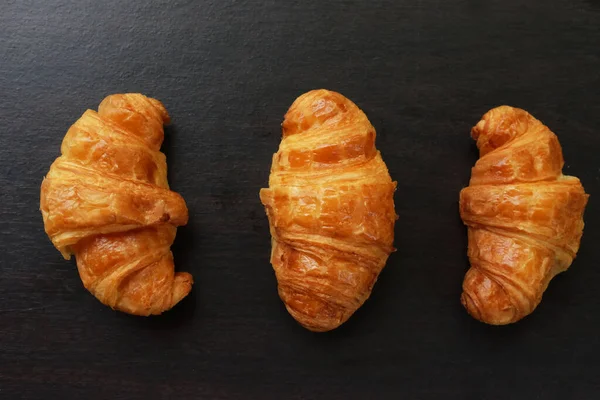 Τρία Κρουασάν Ψωμί Στο Μαύρο Ξύλινο Φόντο Πρωινό Έννοια — Φωτογραφία Αρχείου