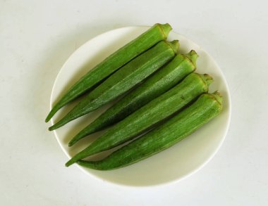 young raw okra, ladys finger, gombo, gumbo, bendee, quimbamto (hisbicus esculentus l.) vegetables On the plate .flat lay