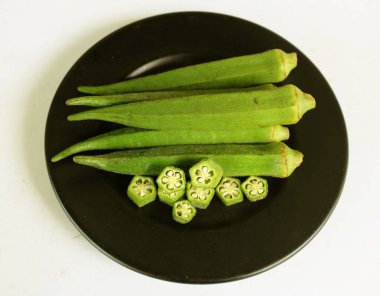 young raw okra, ladys finger, gombo, gumbo, bendee, quimbamto (hisbicus esculentus l.) vegetables On the plate .flat lay