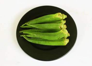 young raw okra, ladys finger, gombo, gumbo, bendee, quimbamto (hisbicus esculentus l.) vegetables On the plate .flat lay