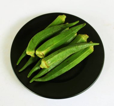 young raw okra, ladys finger, gombo, gumbo, bendee, quimbamto (hisbicus esculentus l.) vegetables On the plate .flat lay