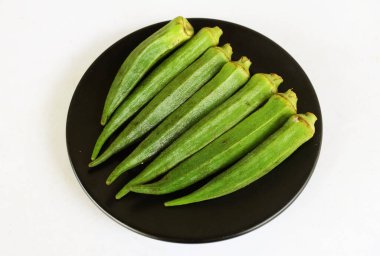 young raw okra, ladys finger, gombo, gumbo, bendee, quimbamto (hisbicus esculentus l.) vegetables On the plate .flat lay
