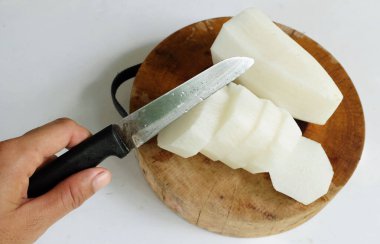 Asyalı kadının eli taze beyaz daikon, daikon turpu, beyaz turp (raphanus sativus var. Beyaz arka planda kesme tahtasındaki dilimler. Düz yatıyordu.