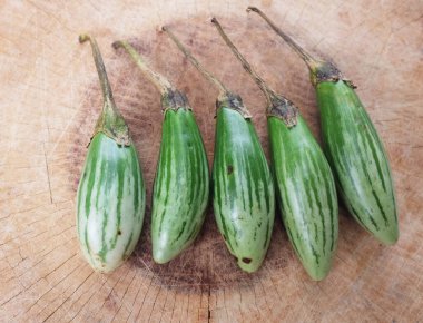 Bir parmak patlıcanı (solanum melongena) kahverengi bir tahta kesme tahtasına kapatın