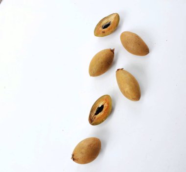 Yarı kesilmiş ve yeşil yapraklı bir grup taze organik tatlı meyve, sapodilla eriği, sapota (l) p. royen), sapodilla, sawo beyaz zemin üzerinde izole edilmiş.