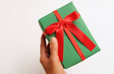 Kırmızı kurdeleli yeşil hediye kutusu beyaz arka planda.