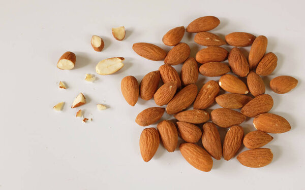  a heap of brown raw almonds nuts  isolated on white backdrop