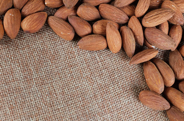 top view a heap of brown raw almonds nuts  on linen fabric isolated on white backdrop