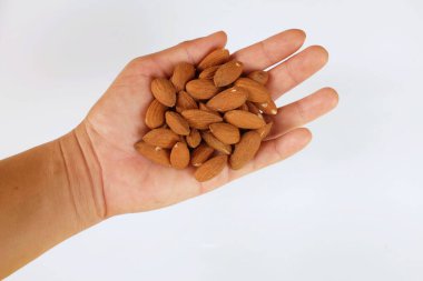 Düz bir yığın kahverengi çiğ badem uzanıyordu. Elinde fındıklar, beyaz arka planda izole edilmiş bir insan vardı.