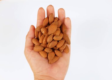 Düz bir yığın kahverengi çiğ badem uzanıyordu. Elinde fındıklar, beyaz arka planda izole edilmiş bir insan vardı.