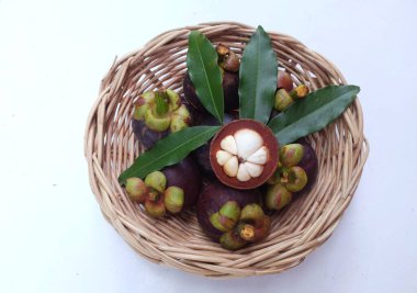 Taze, sulu, sulu, mangosteen meyveler (Garcinia mangostana L.) Tüm mangosteen ve ahşap bir sepette ikiye kesilmiş, beyaz bir zemin üzerinde Meyve Kraliçesi olarak bilinir.