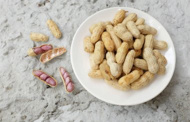 Organik fıstık, kabuklu ve haşlanmış fıstık, amendoim cozido, serpe, nordeste, brrazil (arachis hipogaea l.) beyaz tabakta çimento zemininde izole edilmiş.