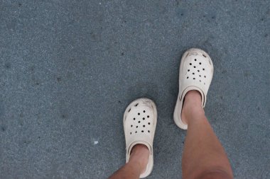 Özelleştirilebilir yaz plajı giyen Asyalı bir kızı kapayın pürüzsüz kumsalda lastik ayakkabılar giyin.