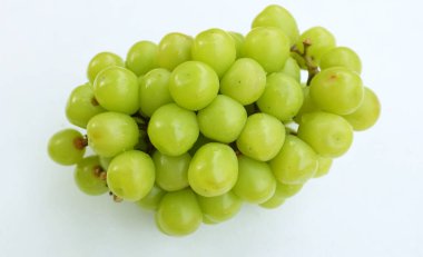 Bir demet taze tatlı yeşil muscat (Vitis vinifera) üzümü, beyaz bir arkaplanda izole edilmiş yapraklarla. Yeşil üzümler. Japon üzümleri. Üzüm yeşili. Tadı tatlı ve doğal..