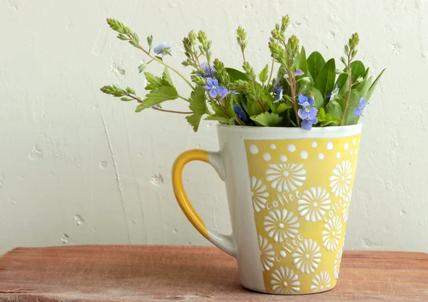 Blommor i en gul kopp — Stockfoto
