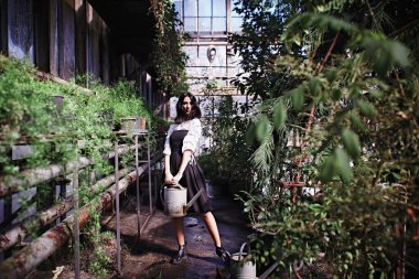 Şirin bir kız elinde demir sulama kabıyla sebze bahçesinde duruyor. Bitkileri sulamak için su var. Bahçıvan kadın. 