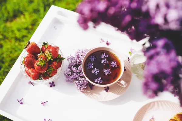 French strawberry and  tea cup with lilacs flowers. Morning mood. Beautiful breakfast time.Top view. The concept of delicious and healthy food. Selective focus art noise