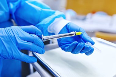 Dişçinin elinde lokal anestezi için şırınga var. 