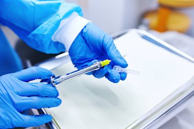 Dişçinin elinde lokal anestezi için şırınga var. 