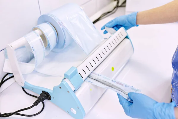Sterilizing box. Sterilization of instruments. Dentist tools. Sterilization procedure. Hands in blue gloves holding dentist tools.