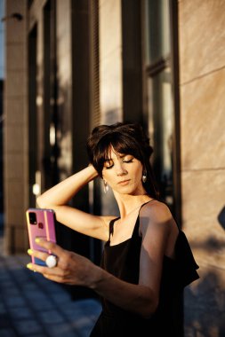 Genç, güzel esmer kadın kamerayla selfie çekiyor. Moda sokağı. 