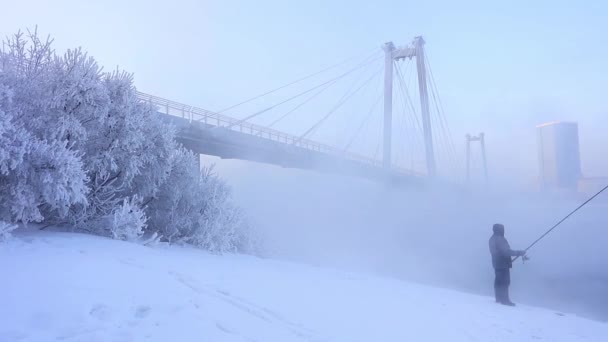 Bybrua over elven om vinteren. Bylandskap med bro over elven og en svært kald sesong – stockvideo
