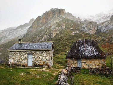 Çoban kulübeleri Lago del Valle 'de, dağlarda biraz kar, Somiedo Doğal Parkı ve Biyosfer Rezervi, Asturias, İspanya
