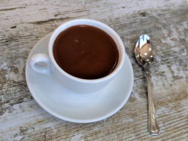 Cup of hot chocolate seen from above on a light-colored aged wooden table