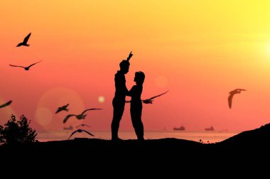 Siluet çiftler ve deniz kenarında gün batımı ışığı.