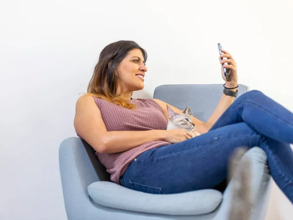 latin young woman sitting in a chair with a cat, in a video call