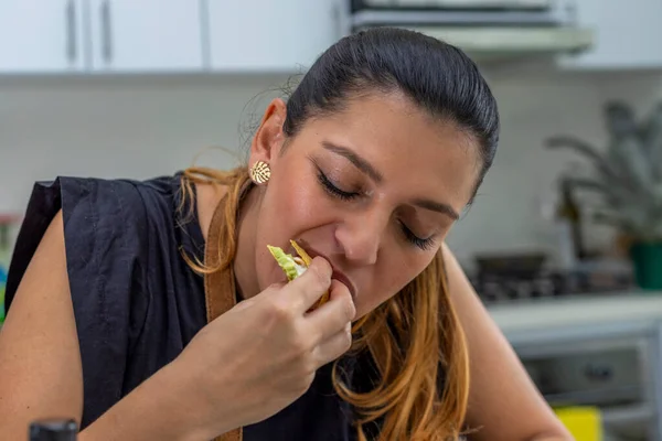 Jovem mulher comer um taco acabado de preparar na cozinha — Fotografia de Stock