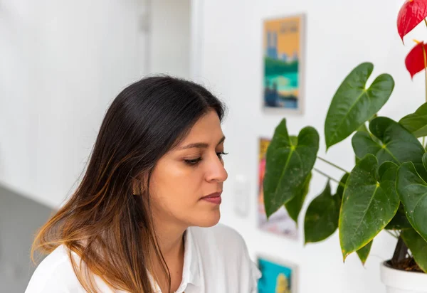 portrait of young latina woman in home near to indoor plants