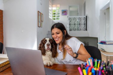 Gülümseyen Latin kadın ev ofisinden köpeğini gösteren bir video mesajı alıyor.