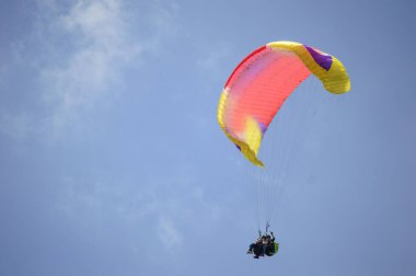 Ufukta bulutlar olan açık mavi gökyüzünde paraşütle atlamak