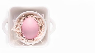 Paskalya tatili konsepti açık arkaplan pembe yumurta talaş içinde minimalist tarzda fotokopi alanı ile