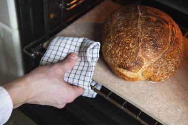 Adam fırından ev yapımı sıcak ekmek çıkarıyor.