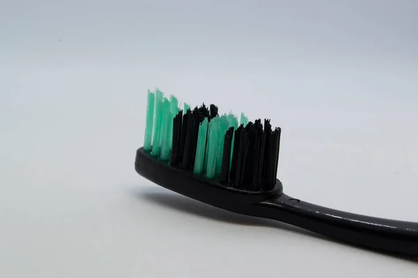Beyaz arkaplanda siyah bir diş fırçası.