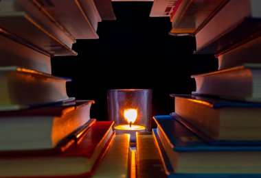 Çerçeve kitaplardan yapılmış ve ortasında bir mum yanıyor..