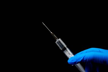 Siyah bir arka planda, bir şırınganın ellerinde..