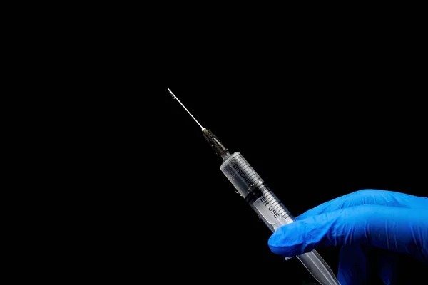 Siyah bir arka planda, bir şırınganın ellerinde..