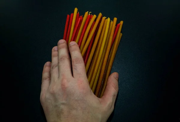 El ince sarı ve kırmızı mumları tutar..