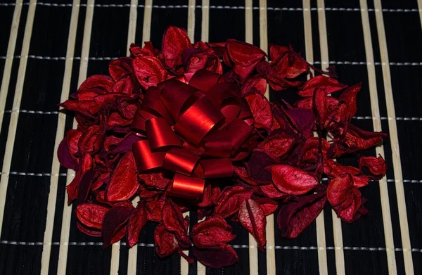 Kırmızı yapraklar siyah kamış peçetede, üstünde kırmızı bir hediye yayı var..