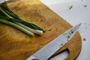 Mutfak bıçağıyla kıyma tahtasına yeşil soğan dizdim..