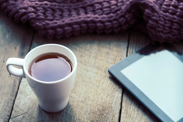 Beyaz fincan çay, dijital tablet ve eşarp eski ahşap masa