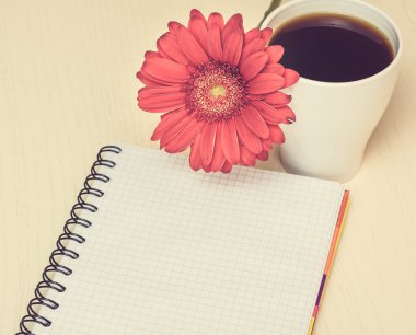 Pembe gerbera çiçek, fincan kahve ve ahşap des notebook