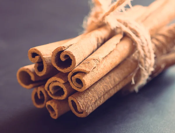 Manojo de palitos de canela sobre fondo negro — Foto de Stock