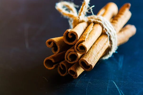 Manojo de palitos de canela sobre fondo negro — Foto de Stock