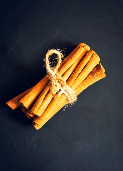 Manojo de palitos de canela sobre fondo negro — Foto de Stock