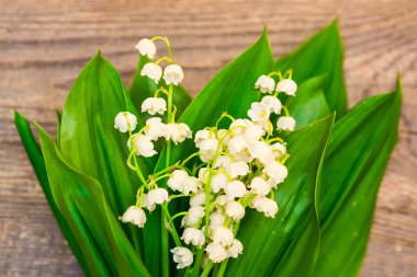 Ahşap arka plan üzerinde vadideki zambak buketi. Bahar