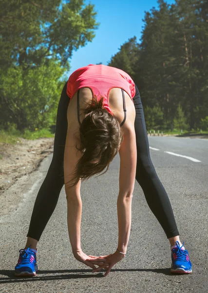 Genç fitness kadın runner Koşudan önce germe. Runner atlet